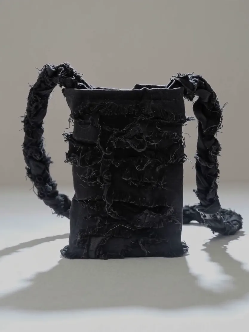A plain product photo of a black denim bag on a white backdrop